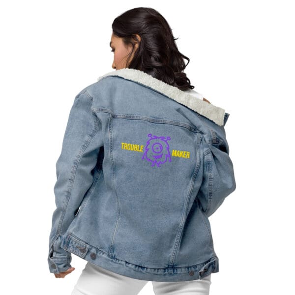 A woman wearing a denim jacket with purple and yellow lettering.